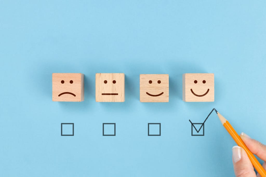 4 wooden blocks showing different emotions to represent levels of high or low employee engagement.