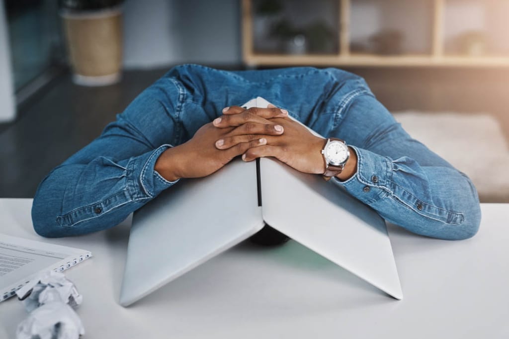 An actively disengaged employee with their head in a computer.