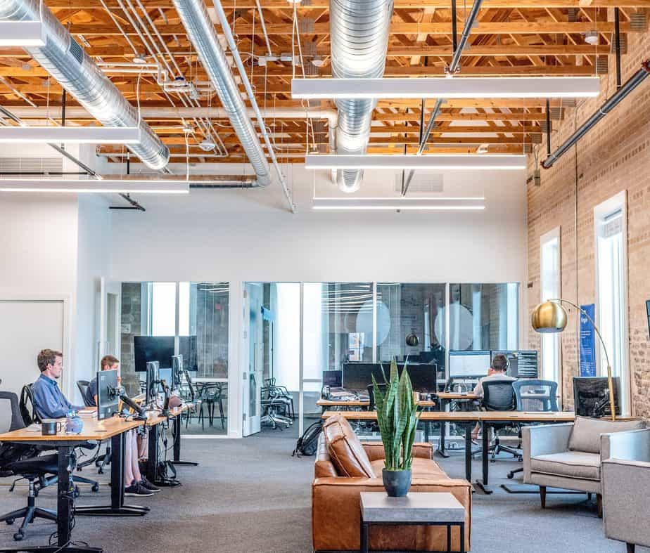 A large, open office space with several desks and 3 men working.