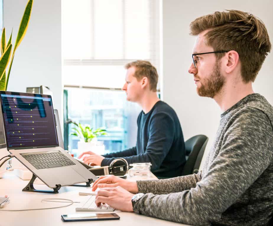 2 men working at a table on their computers.