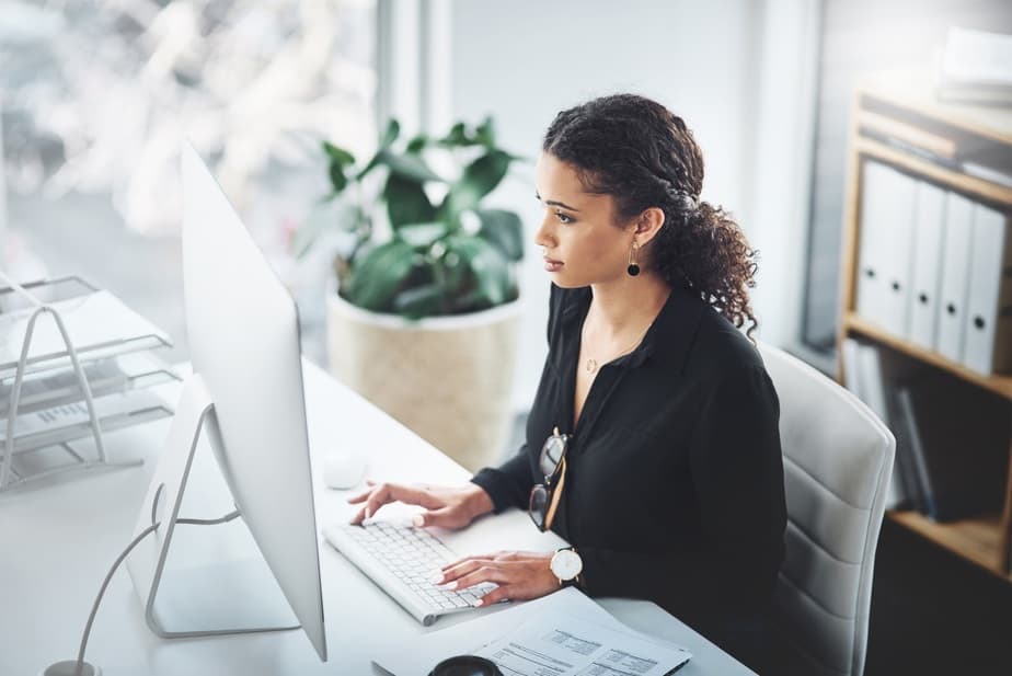 A woman in an office, typing on a keyboard at her desk, using productivity measurement software.