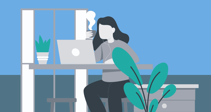 A woman working remotely at a desk, working on a laptop and holding a steaming cup of coffee.