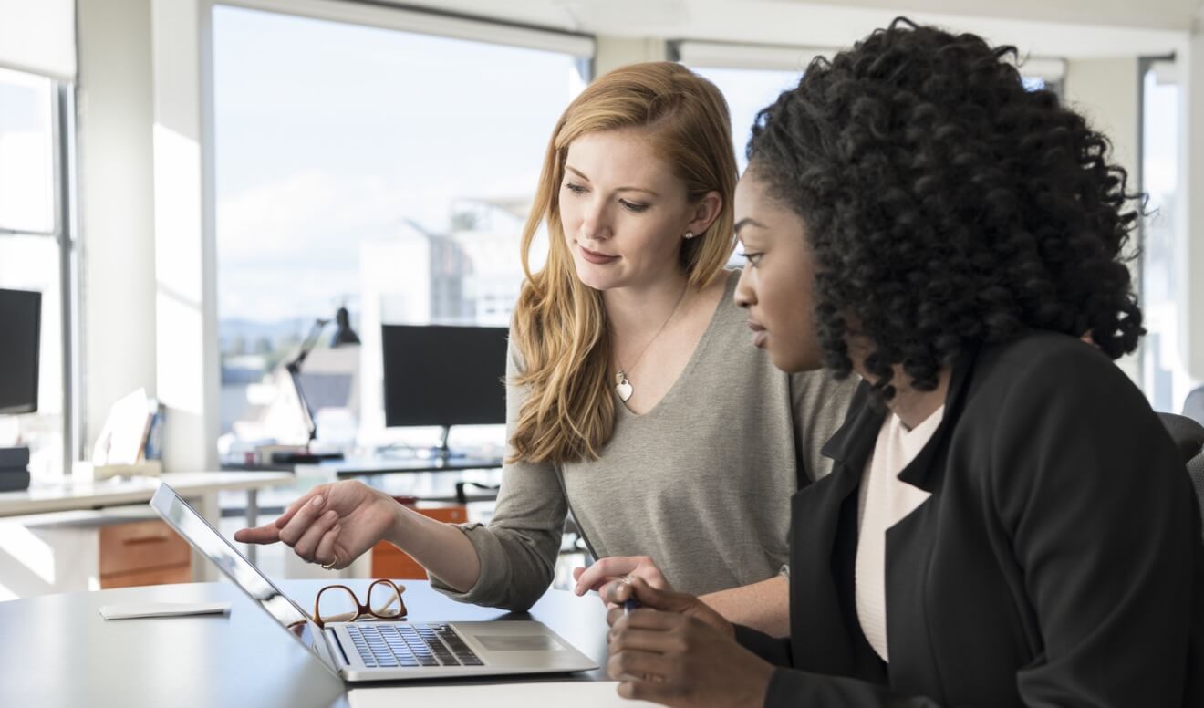 Two female colleagues analyzing workforce data to identify changes to their workplace policy