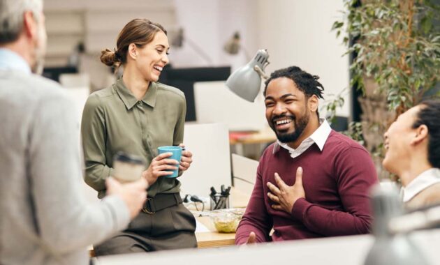 Colleagues laughing and chatting in a modern office.