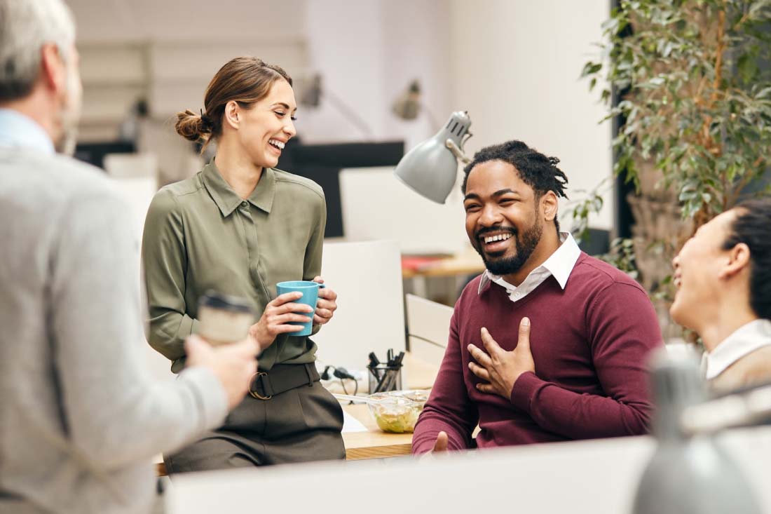 Colleagues laughing and chatting in a modern office.